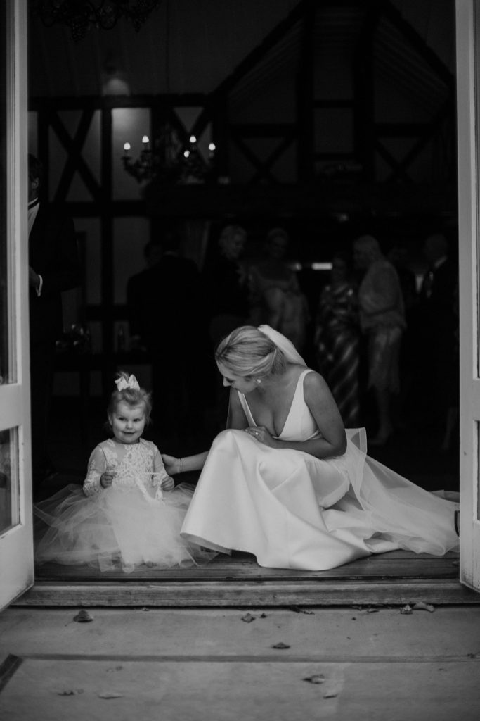 New Zealand wedding with an Anagrassia flower girl wearing Communion alencon lace and champagne tulle Communion style dress with long sleeves and satin buttons