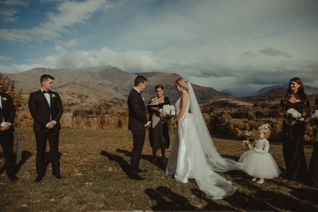 New Zealand wedding with an Anagrassia flower girl wearing Communion alencon lace and champagne tulle Communion style dress with long sleeves and satin buttons