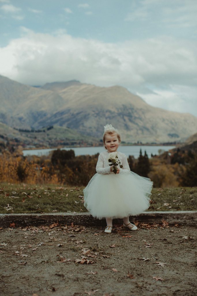 New Zealand wedding with an Anagrassia flower girl wearing Communion alencon lace and champagne tulle Communion style dress with long sleeves and satin buttons