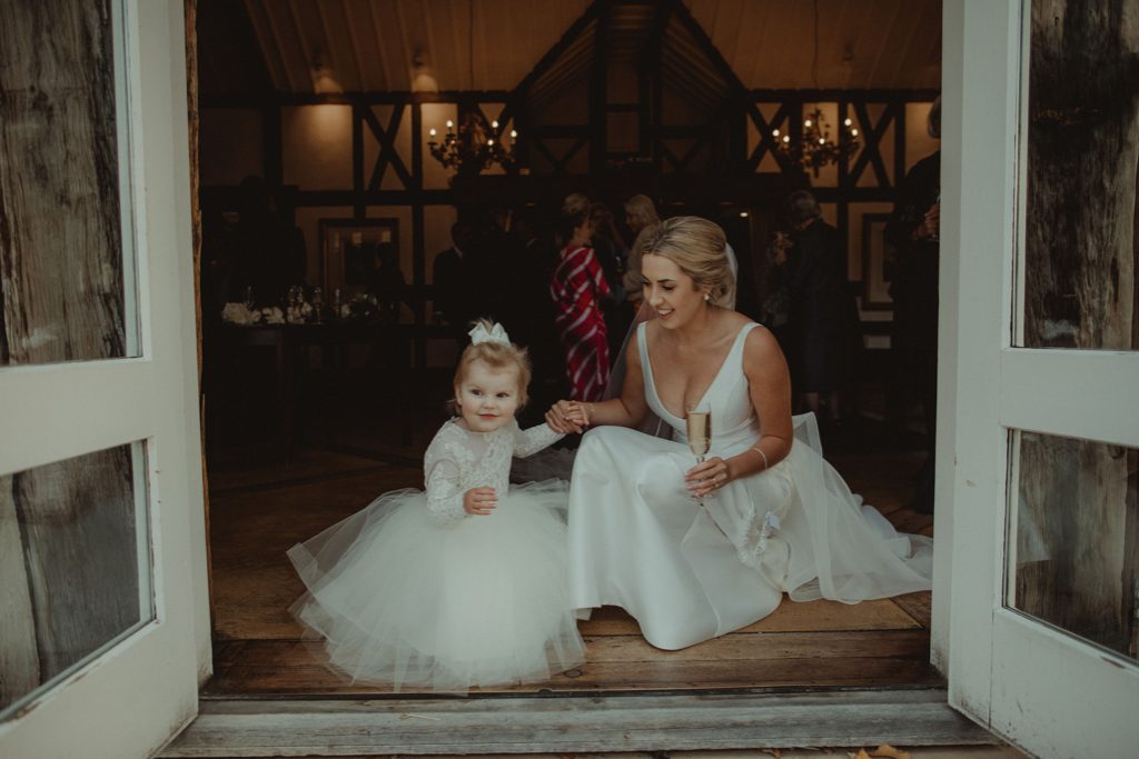 New Zealand wedding with an Anagrassia flower girl wearing Communion alencon lace and champagne tulle Communion style dress with long sleeves and satin buttons