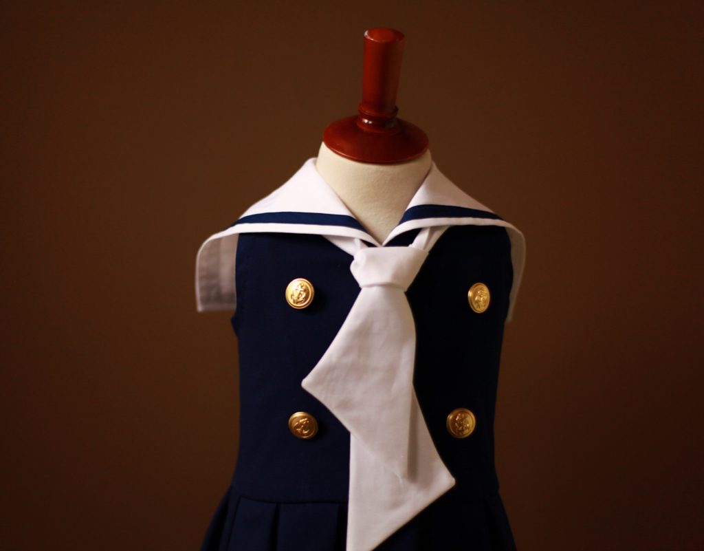 Best sleeveless navy girls sailor nautical dress with white collar, tie, drop waist pleated skirt, and gold buttons for Memorial, Independence, and Labor Day