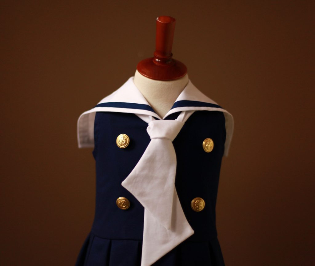 Best sleeveless navy girls sailor nautical dress with white collar, tie, drop waist pleated skirt, and gold buttons for Memorial, Independence, and Labor Day