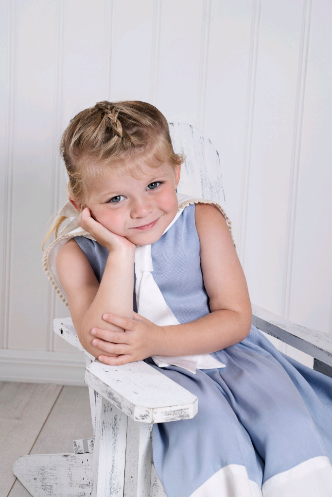 A little girl in a light blue and white sailor dress sleeveless